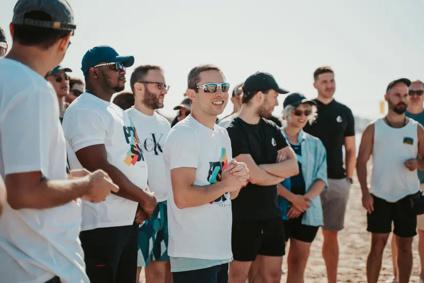 A large group of Prisma team members gathered on a beach during a company retreat